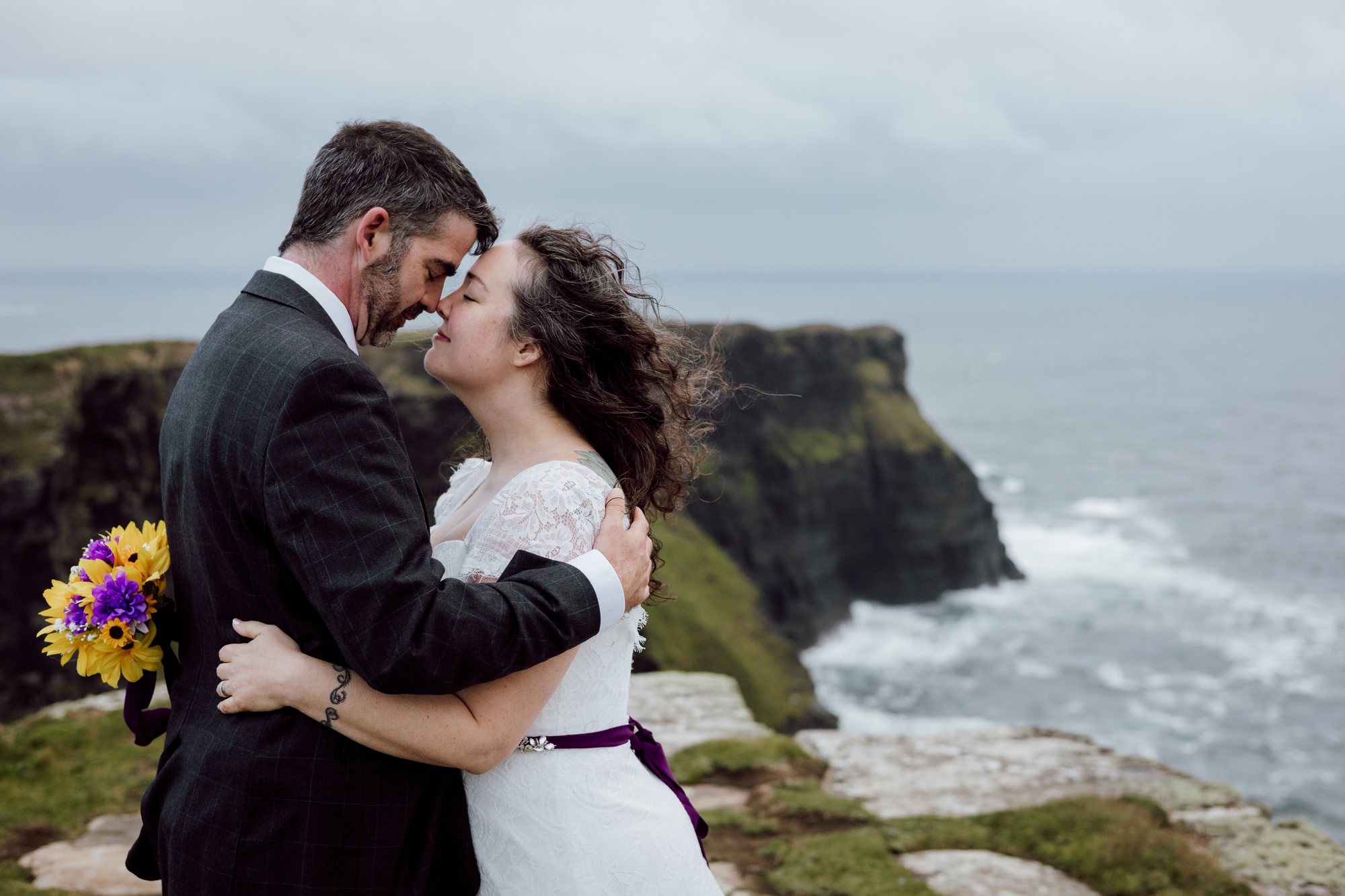 Newlyweds embracing above the Atlantic cliffs