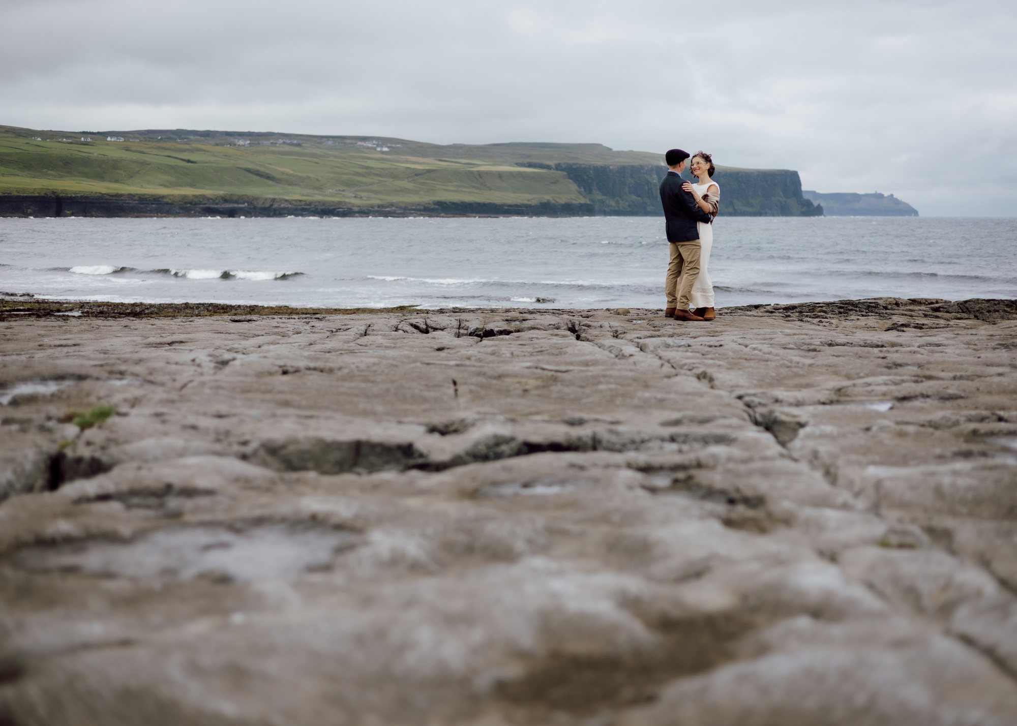 Couple dancing beside the sea beneath a wide sky