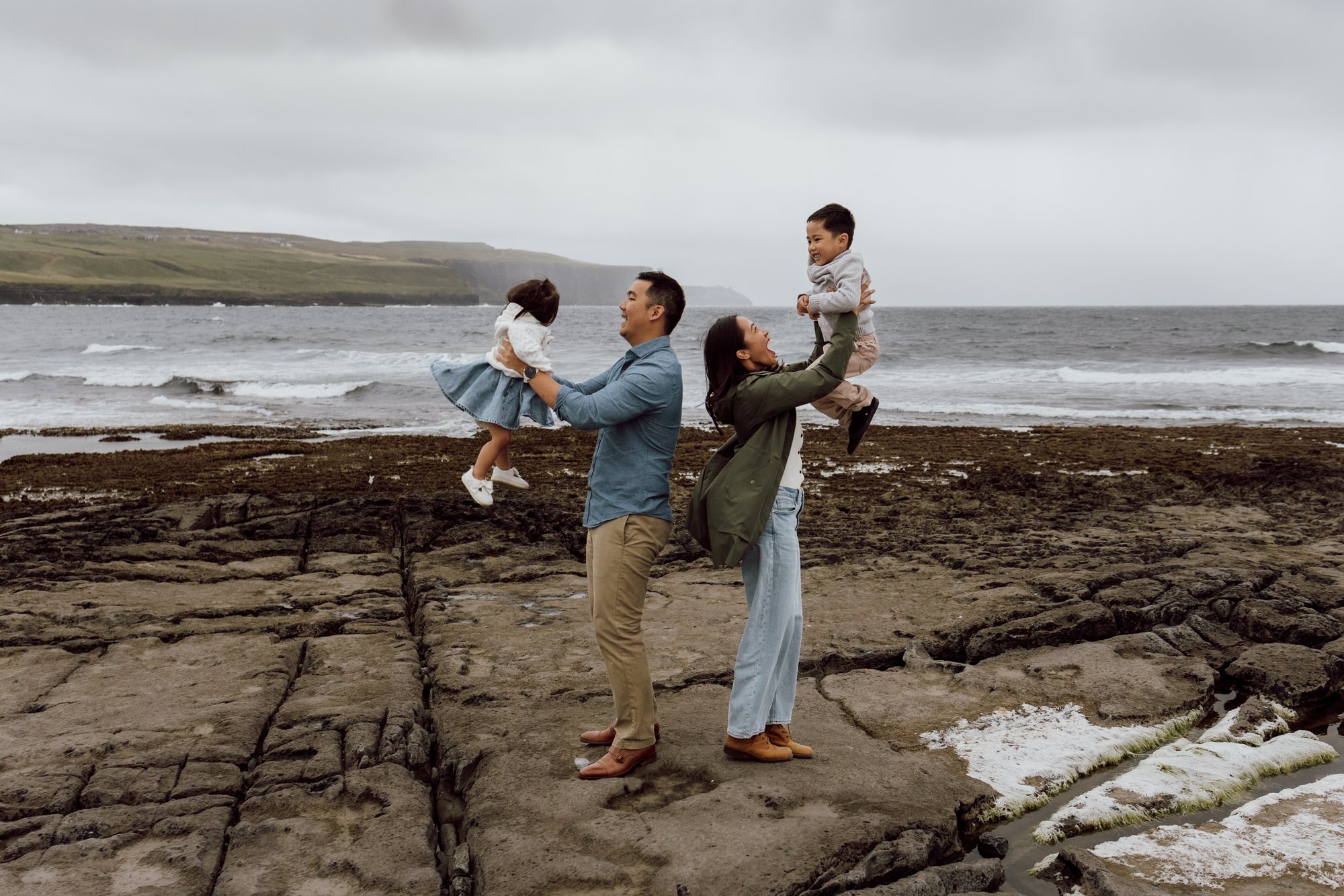 Family lifting their children beside the Atlantic