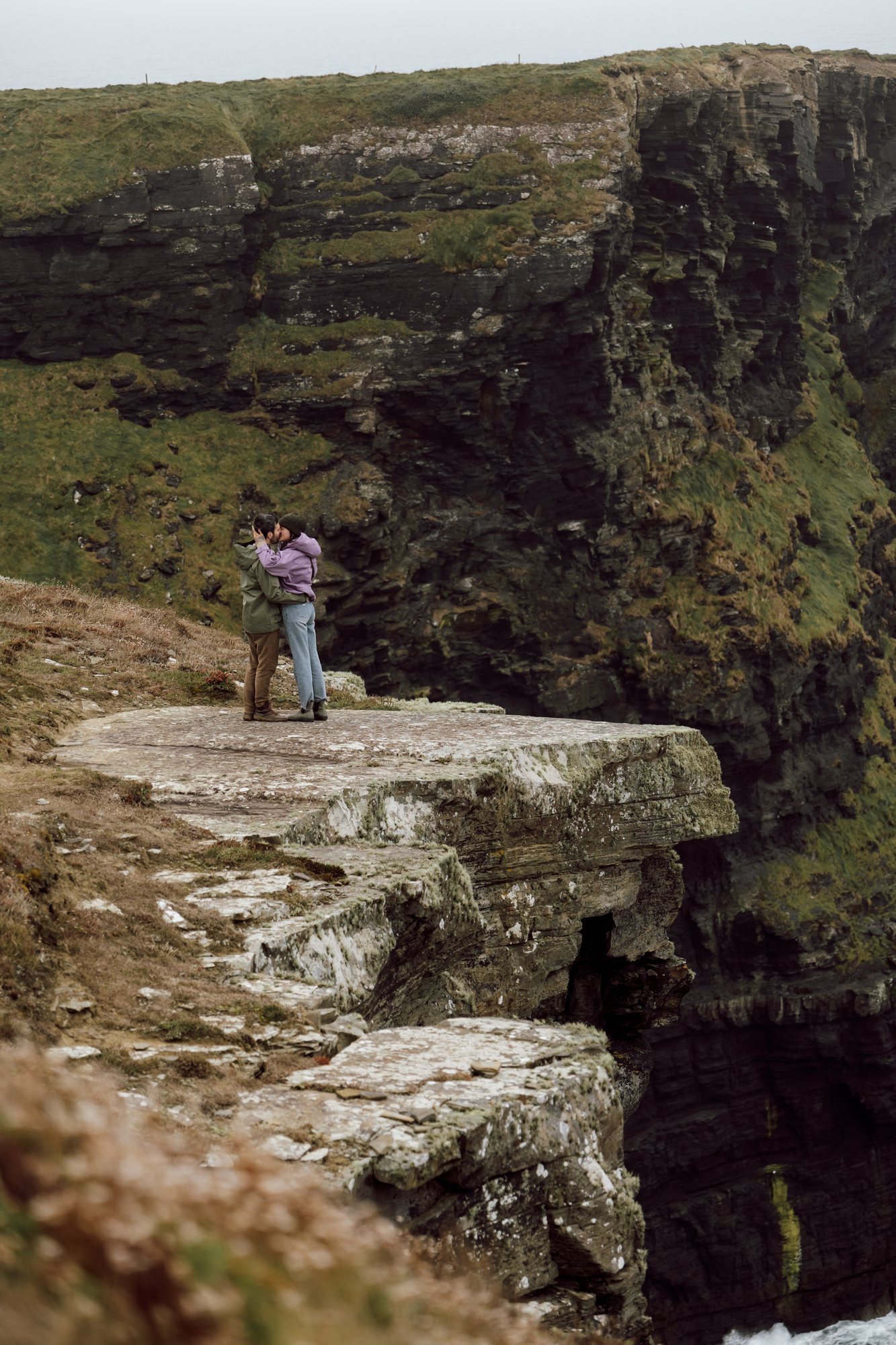 Couple embracing on the edge of an Irish cliff